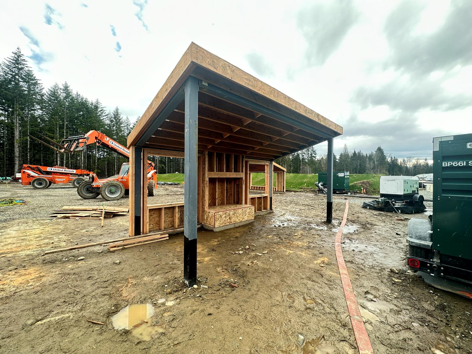 Wood-framed amenity structure on steel posts with exposed rafters, framed by Twin Brothers Group