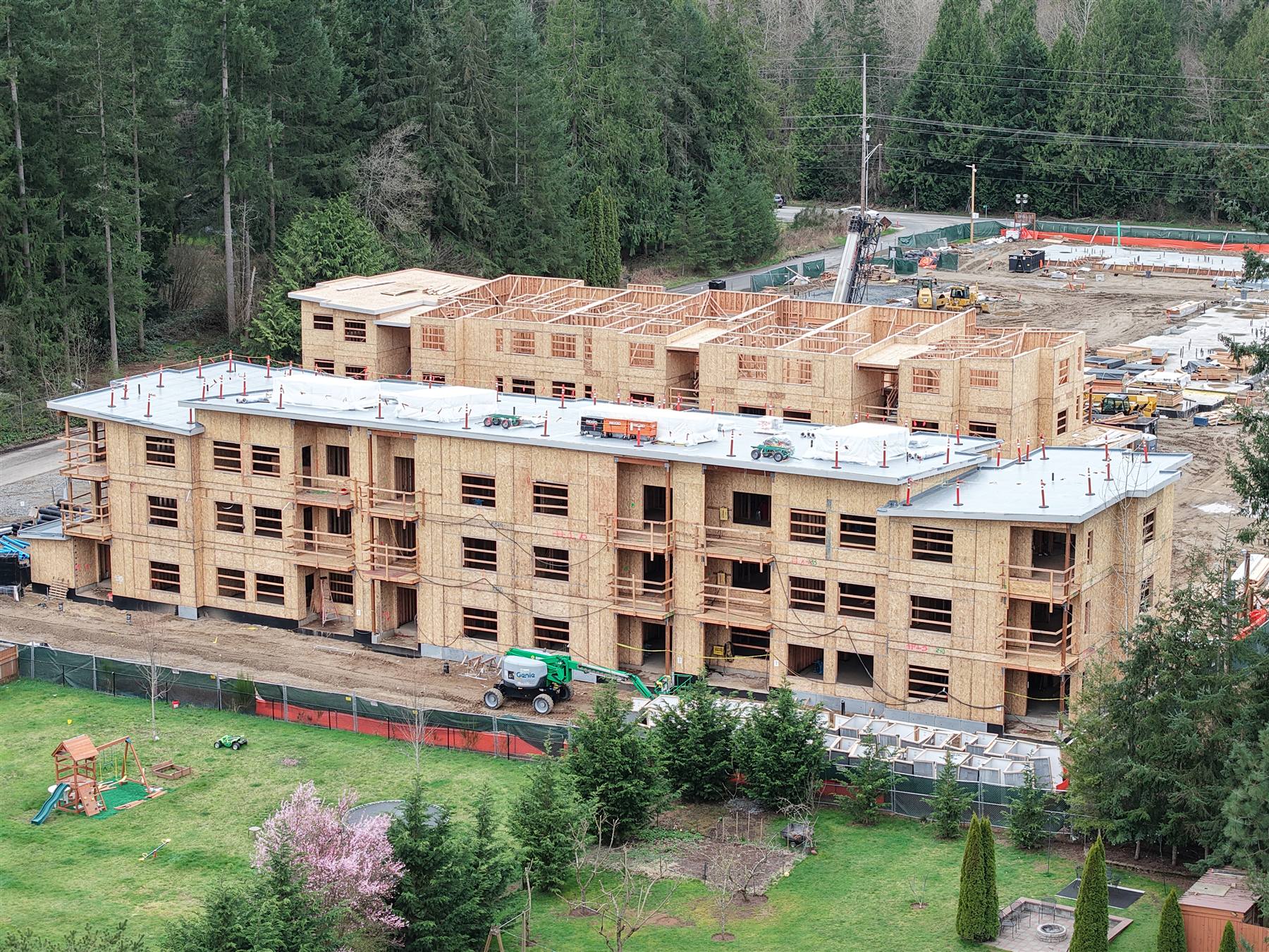 Three-story wood-frame apartment buildings fully framed by Twin Brothers Group, aerial view, Greater Seattle Area