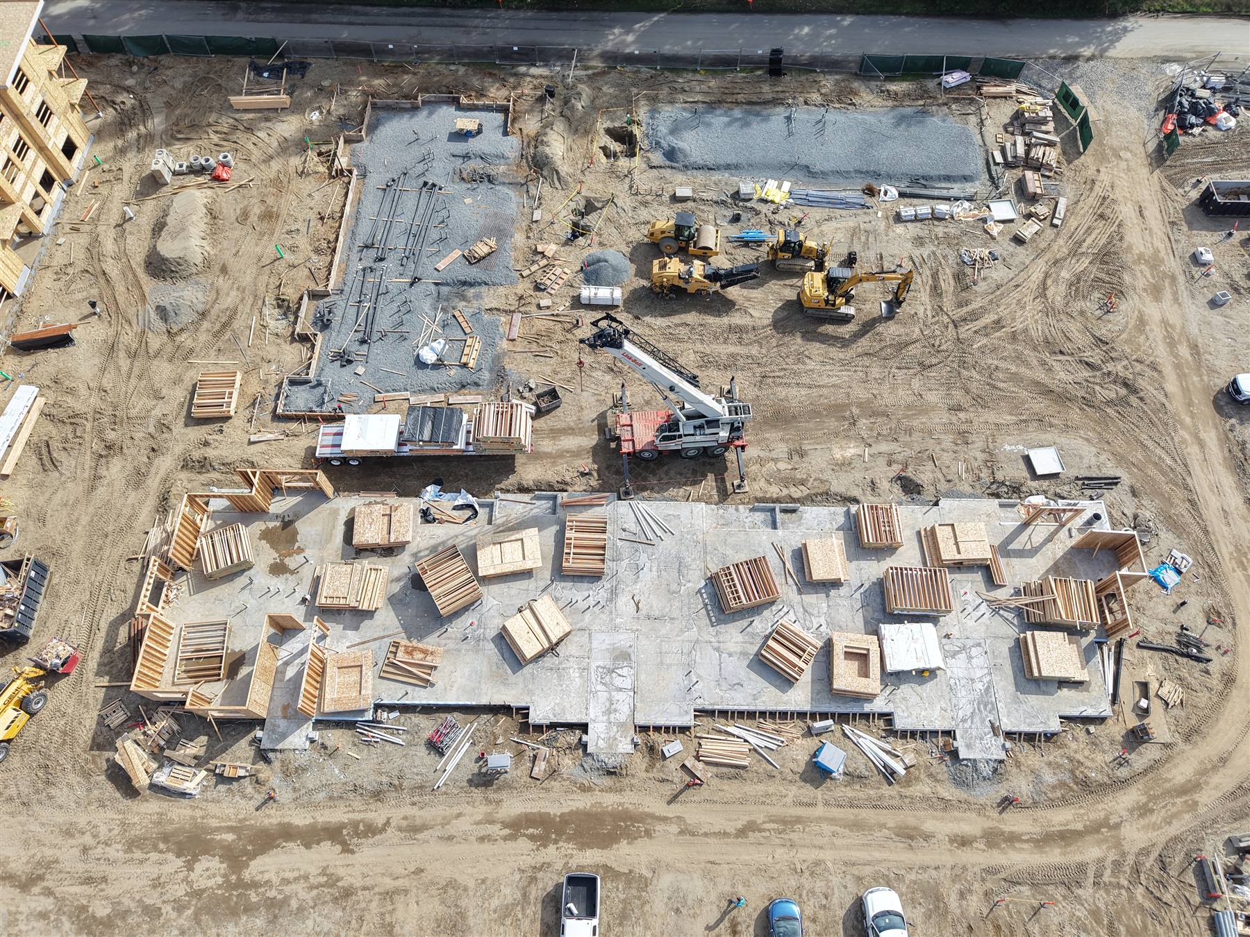 Top-down aerial of foundations with framed wall panels staged flat across the slab