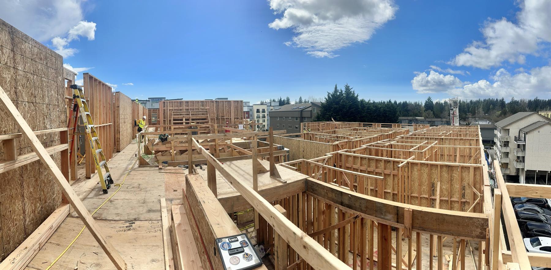 Panorama from the deck of a multifamily building under framing, interior walls and shear walls standing under blue sky
